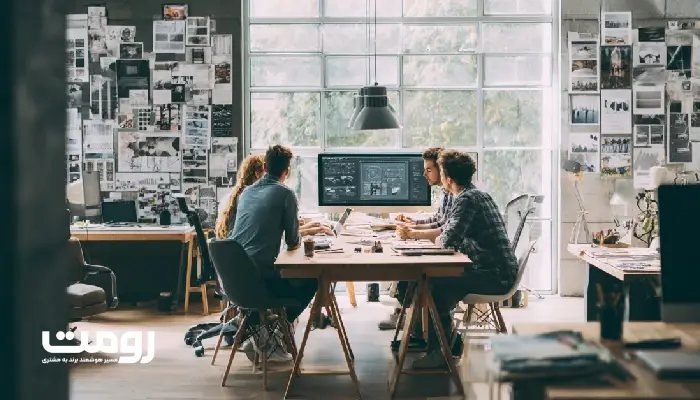 فضای خلاقانه یک آژانس دیجیتال که طراحان در حال بررسی طرحهای اولیه وبسایت و رنگبندی برند هستند.